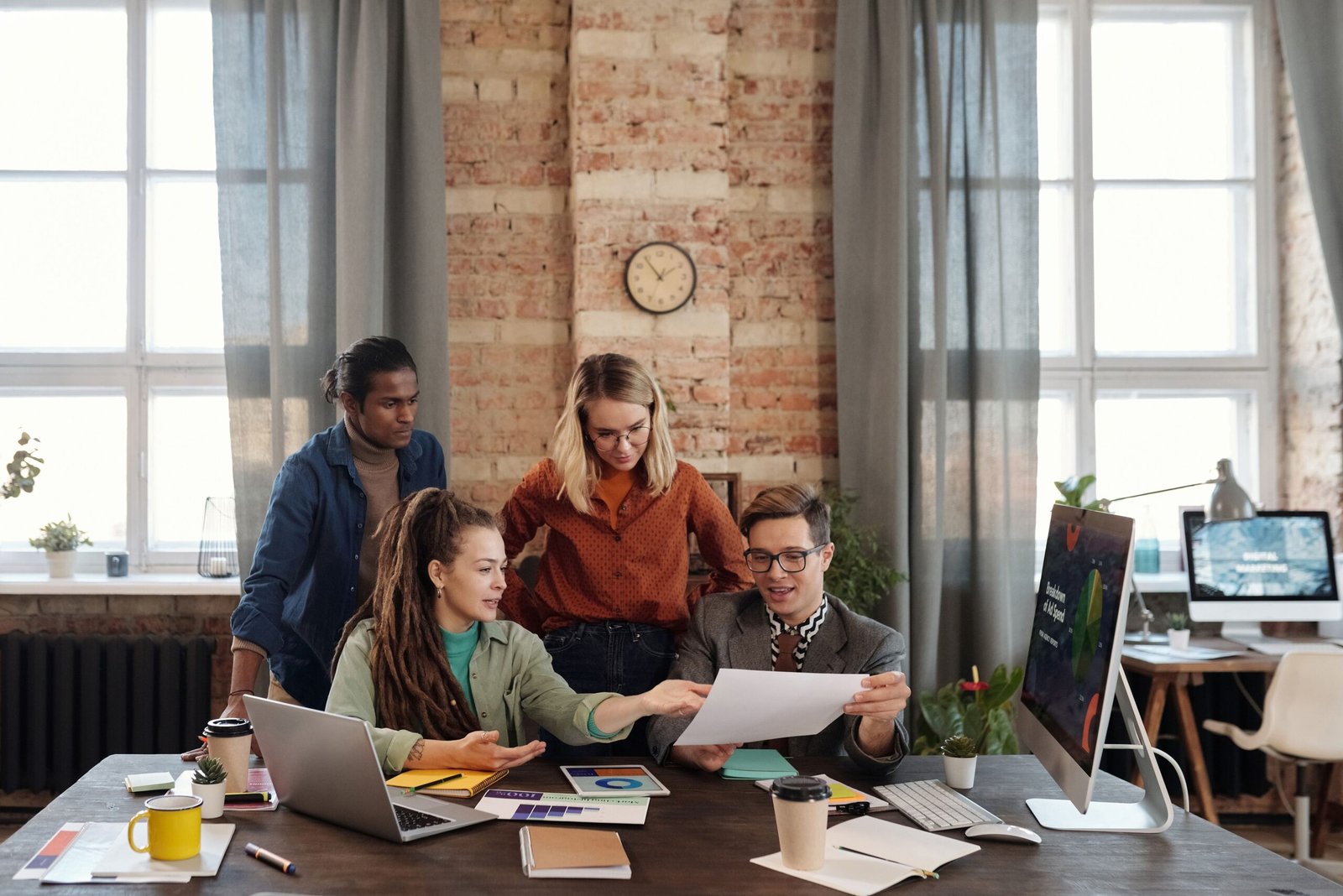 Group of coworkers collaborating around a table in a bright brick-walled office