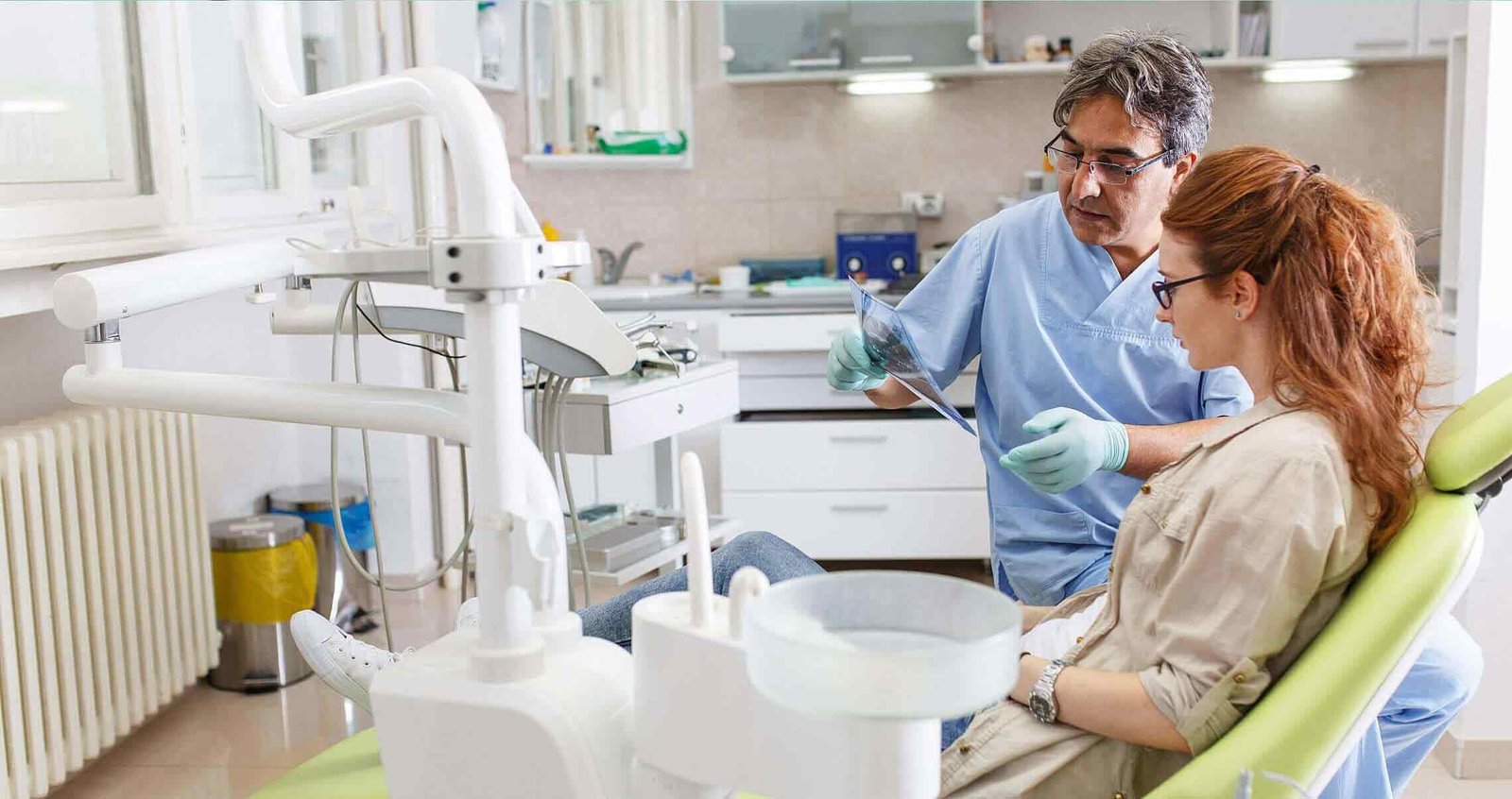Dentist shows a dental X-ray to a patient in a clinic setting.